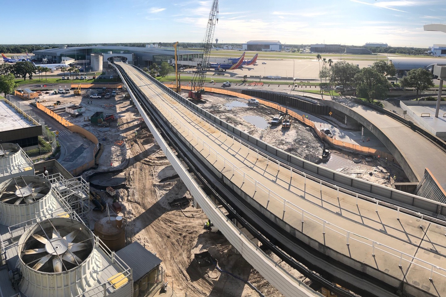 Tampa International Airport construction site featuring elevated roadway, ongoing expansion project, and heavy machinery in a busy urban environment.