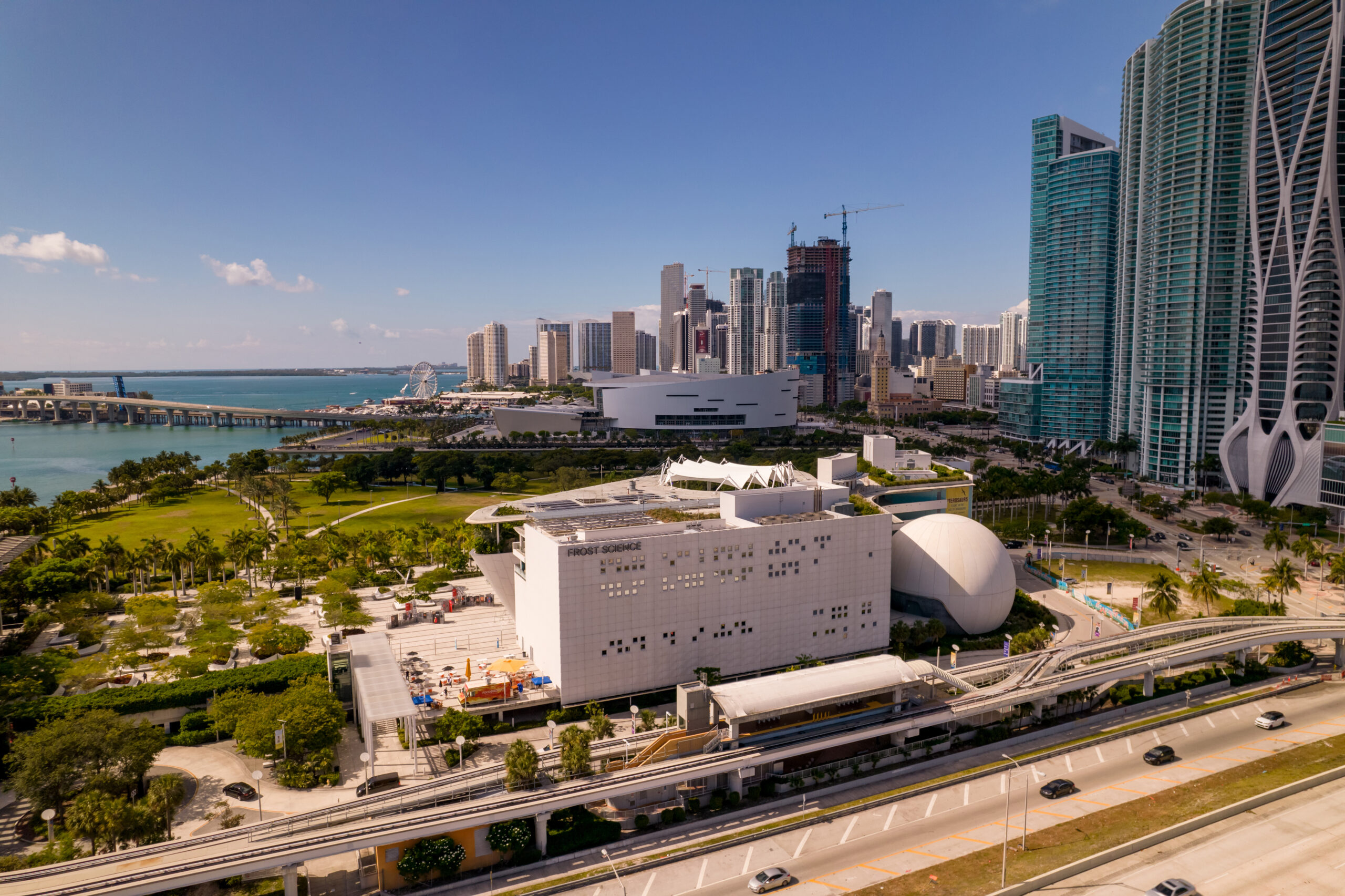 Miami skyline featuring the Frost Science Museum, adjacent park, and urban development along the waterfront.
