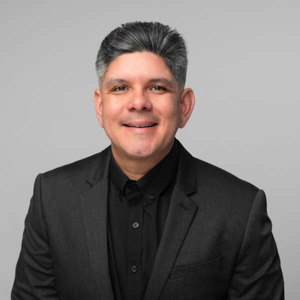 rocky-zapata-safety-profile Rocky Zapata, President of Rocky Zapata Safety Consultants, smiling in a professional black suit against a neutral background, emphasizing leadership in occupational safety and health.