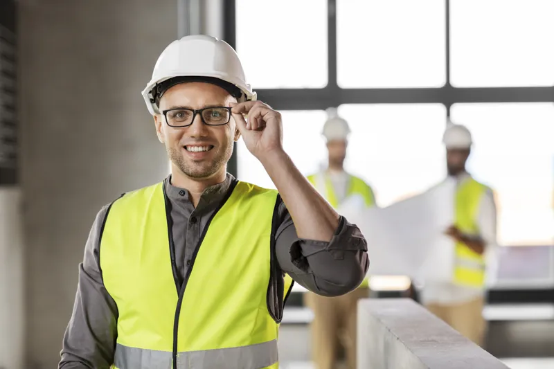 Construction safety consultant in hard hat and safety vest, assessing workplace compliance.